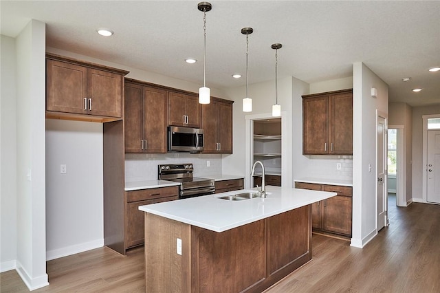 kitchen with wood finished floors, light countertops, appliances with stainless steel finishes, and a sink