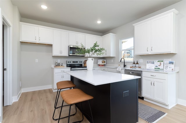 kitchen featuring sink, a breakfast bar area, a center island, stainless steel appliances, and white cabinets