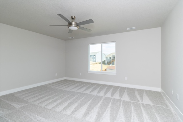 spare room with ceiling fan, light carpet, and a textured ceiling