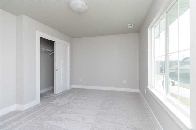 unfurnished bedroom with light colored carpet, a closet, and a textured ceiling