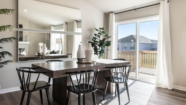 dining room featuring lofted ceiling, wood finished floors, and baseboards