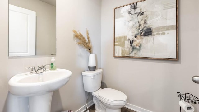 bathroom with baseboards, a sink, and toilet