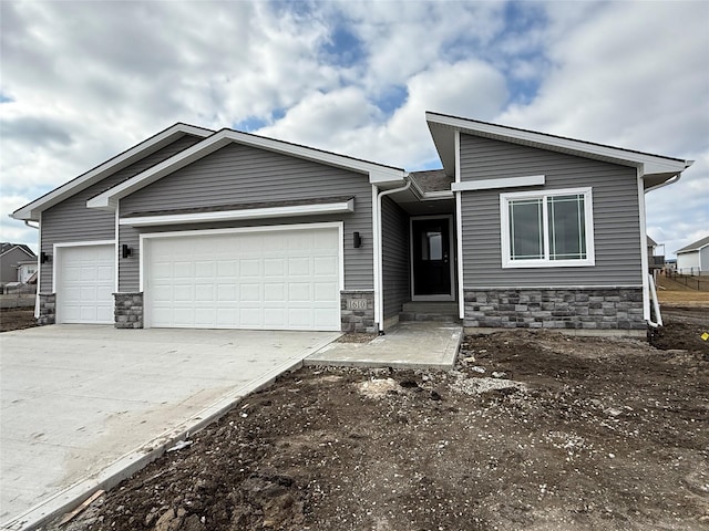 view of front of house with a garage, stone siding, and concrete driveway