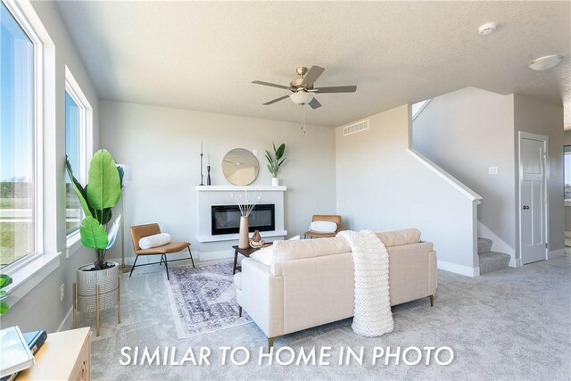 carpeted living room with a textured ceiling and ceiling fan