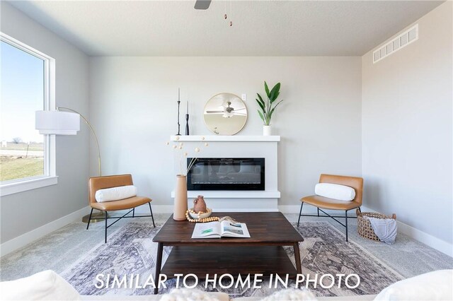 living room with ceiling fan, carpet floors, and a textured ceiling