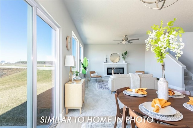 dining space featuring stairs, ceiling fan, carpet, and a glass covered fireplace