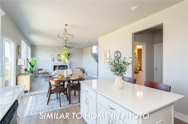 kitchen with light countertops, a kitchen island, white cabinetry, and pendant lighting