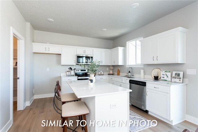 kitchen featuring appliances with stainless steel finishes, a kitchen island, a kitchen breakfast bar, and white cabinetry