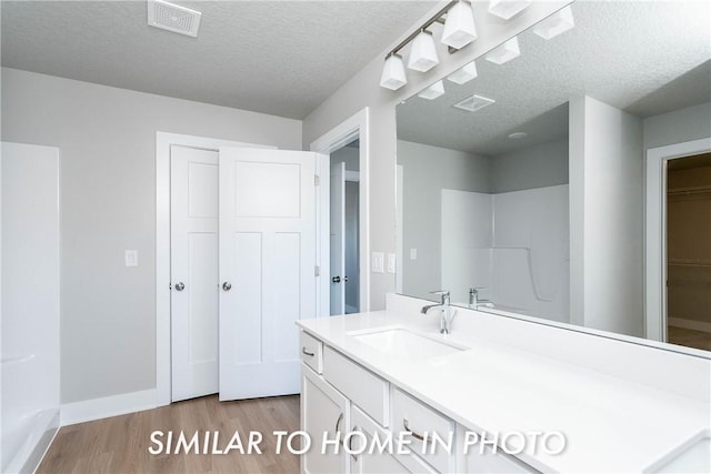 bathroom with visible vents, vanity, a textured ceiling, wood finished floors, and baseboards