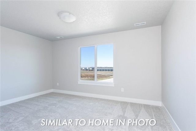 spare room featuring carpet floors, visible vents, a textured ceiling, and baseboards