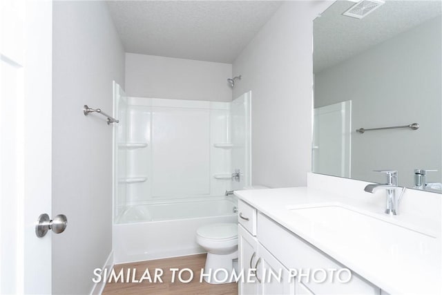 full bath with visible vents, toilet, vanity, a textured ceiling, and wood finished floors