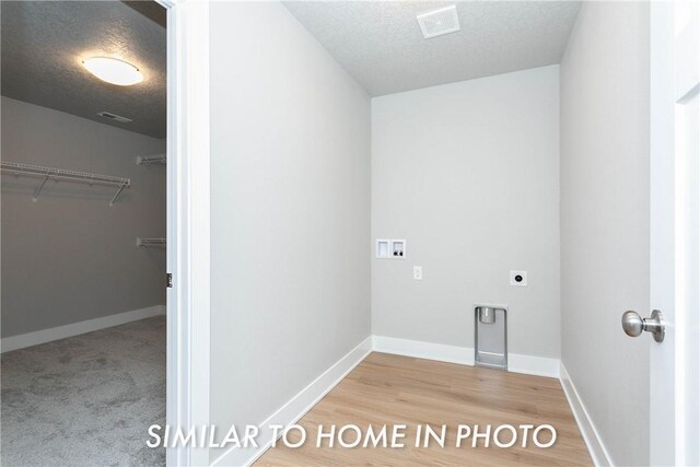 laundry area featuring a textured ceiling, washer hookup, electric dryer hookup, and wood-type flooring