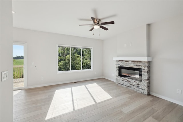 unfurnished living room with ceiling fan, a fireplace, and light hardwood / wood-style flooring