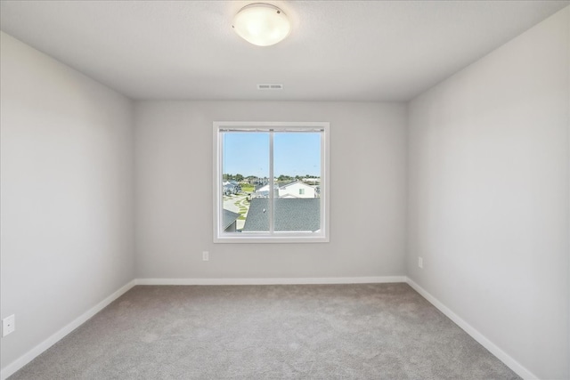 spare room featuring carpet flooring, visible vents, and baseboards