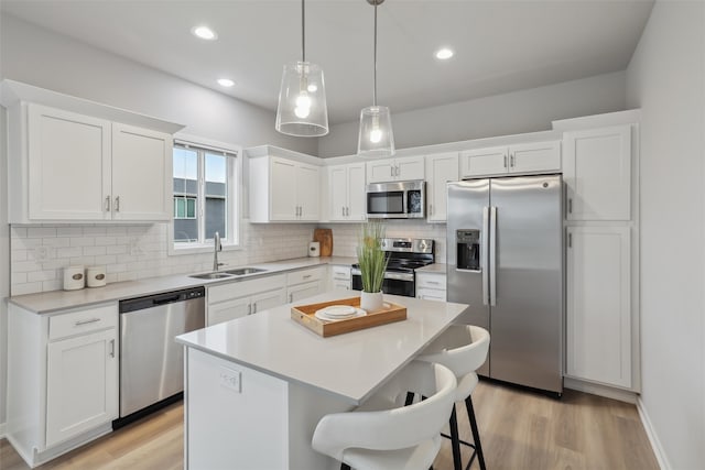 kitchen with white cabinetry, appliances with stainless steel finishes, a sink, and a center island