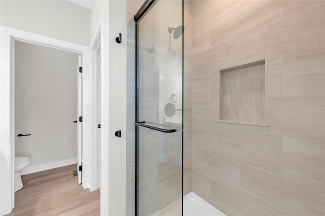 bathroom featuring hardwood / wood-style flooring, toilet, and a shower with shower door