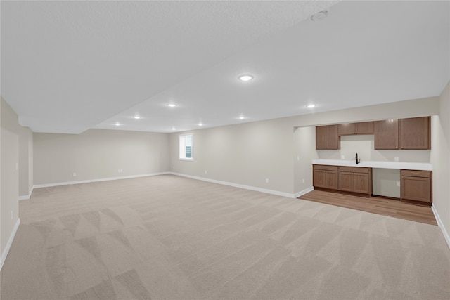 unfurnished living room with light colored carpet and sink