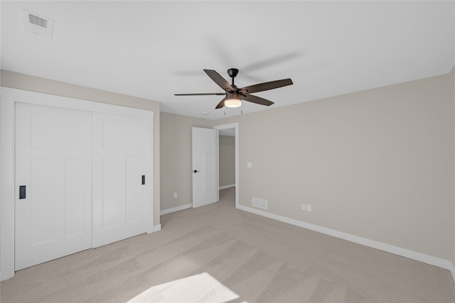 unfurnished bedroom featuring light carpet, a closet, and ceiling fan