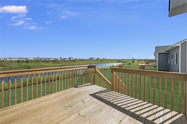 wooden terrace featuring a water view and a lawn