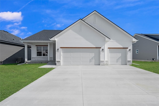 view of front of home featuring a front lawn, central AC unit, and a garage