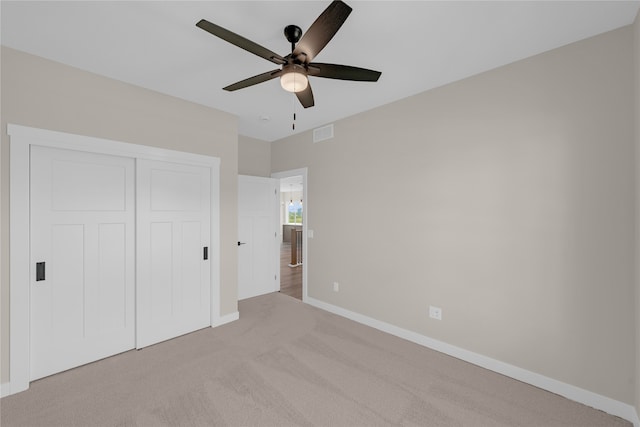 unfurnished bedroom with light carpet, a closet, and ceiling fan