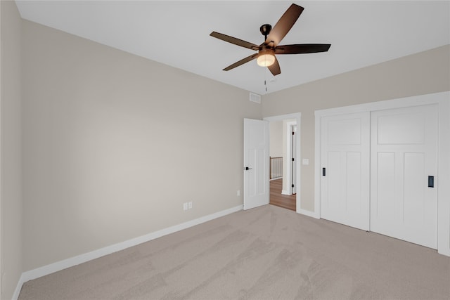 unfurnished bedroom with a closet, light colored carpet, and ceiling fan