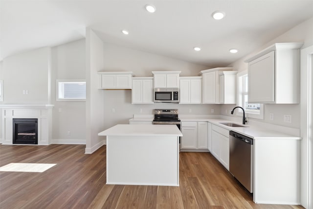 kitchen with a center island, sink, white cabinetry, vaulted ceiling, and appliances with stainless steel finishes