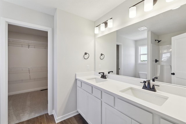 bathroom with wood-type flooring, vanity, toilet, and a shower