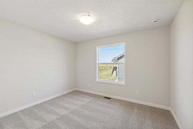 carpeted empty room with a textured ceiling