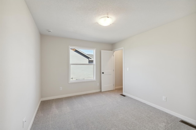 carpeted empty room featuring a textured ceiling