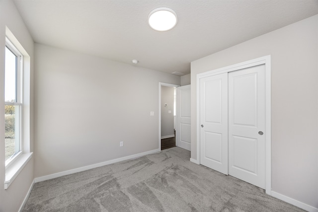 unfurnished bedroom featuring light carpet and a closet