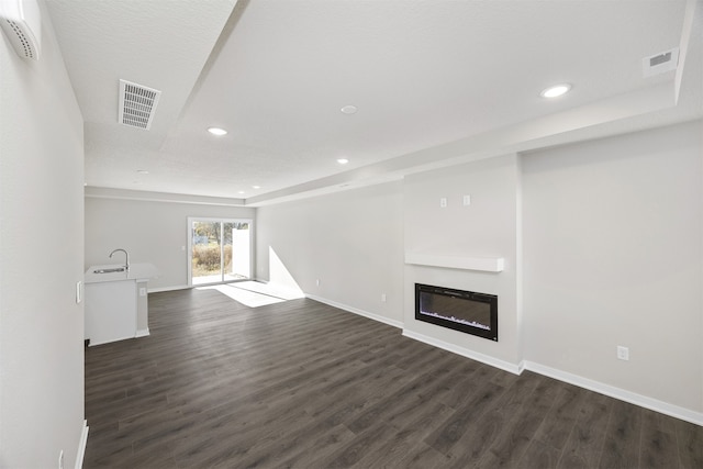 unfurnished living room featuring dark wood-type flooring, a textured ceiling, and sink