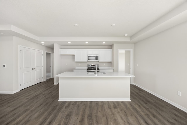 kitchen featuring dark wood-type flooring, white cabinets, sink, an island with sink, and appliances with stainless steel finishes