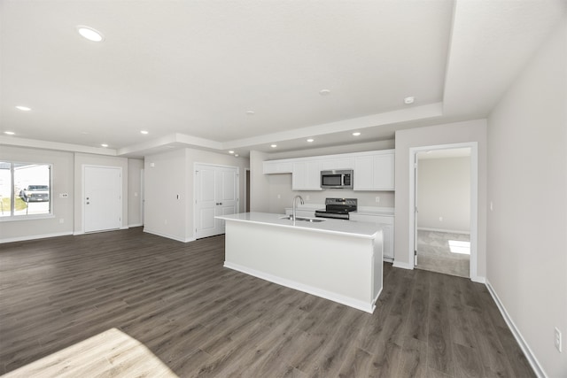 kitchen with stainless steel appliances, dark wood-type flooring, white cabinets, sink, and an island with sink