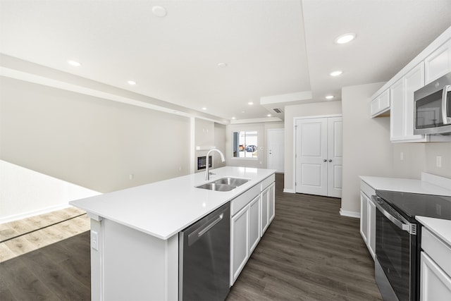 kitchen with stainless steel appliances, a center island with sink, sink, white cabinetry, and dark hardwood / wood-style floors