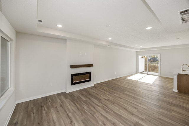 unfurnished living room with wood-type flooring and a textured ceiling