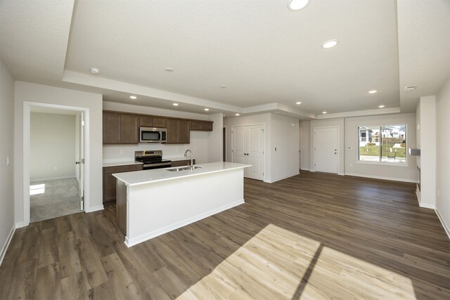 kitchen featuring stainless steel appliances, dark hardwood / wood-style floors, a center island with sink, and sink