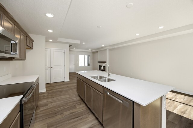 kitchen featuring a center island with sink, sink, appliances with stainless steel finishes, dark hardwood / wood-style floors, and a textured ceiling