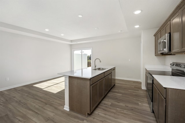 kitchen with dark hardwood / wood-style floors, a center island with sink, sink, and appliances with stainless steel finishes