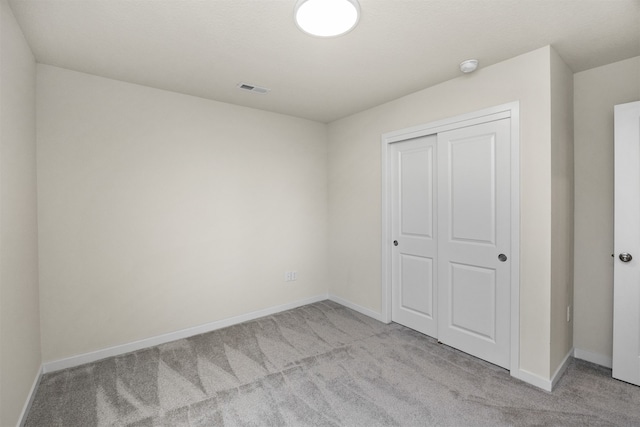 unfurnished bedroom with light carpet and a closet