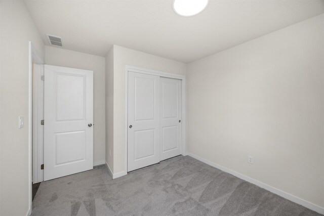 unfurnished bedroom with light carpet and a closet