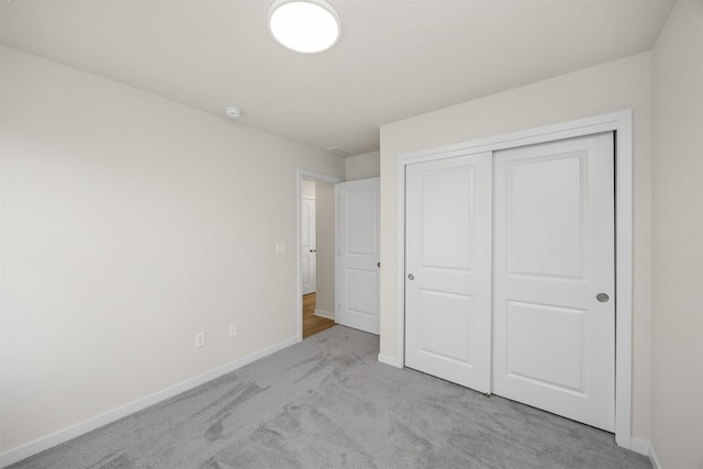 unfurnished bedroom featuring light colored carpet and a closet