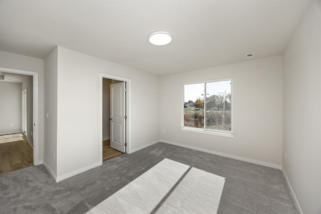 unfurnished bedroom with dark colored carpet and a textured ceiling