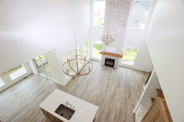 1773 Highland Cir SW, Altoona, IA 50009 - living room with a high ceiling, a fireplace, wood finished floors, a chandelier, and baseboards