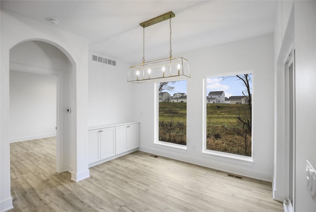 1773 Highland Cir SW, Altoona, IA 50009 - unfurnished dining area featuring arched walkways, light wood finished floors, and baseboards