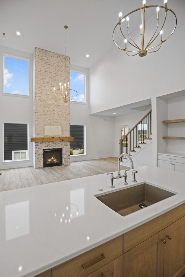 kitchen featuring a high ceiling, sink, a fireplace, decorative light fixtures, and wood-type flooring