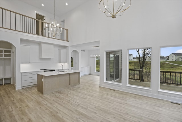 1773 Highland Cir SW, Altoona, IA 50009 - kitchen with a chandelier, a high ceiling, a sink, arched walkways, and light countertops