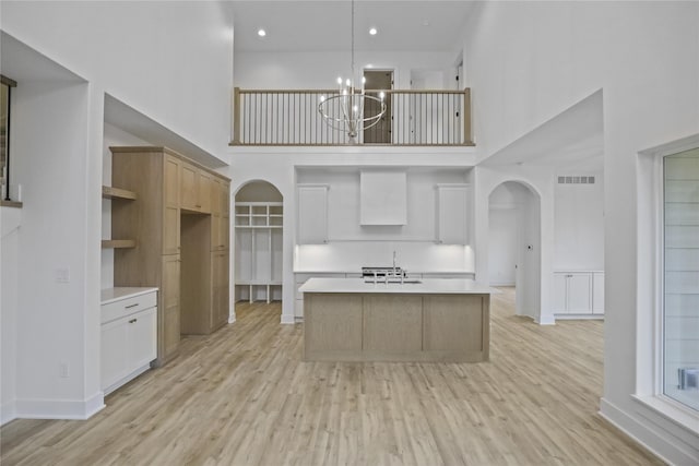 1773 Highland Cir SW, Altoona, IA 50009 - kitchen with arched walkways, a high ceiling, a sink, light countertops, and light wood-style floors