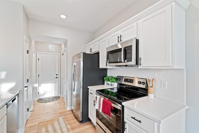 kitchen featuring light wood-type flooring, white cabinets, decorative backsplash, and appliances with stainless steel finishes