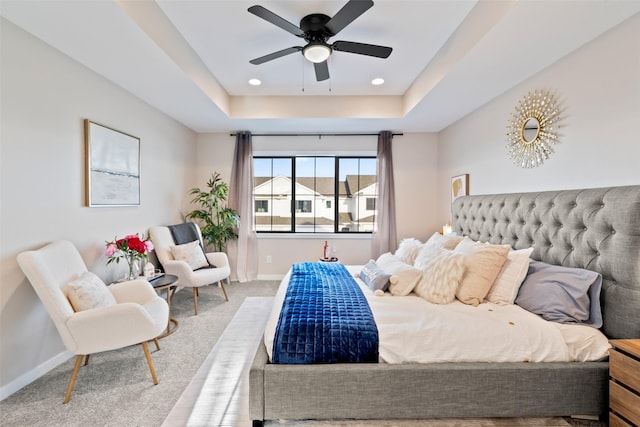 carpeted bedroom with ceiling fan and a tray ceiling